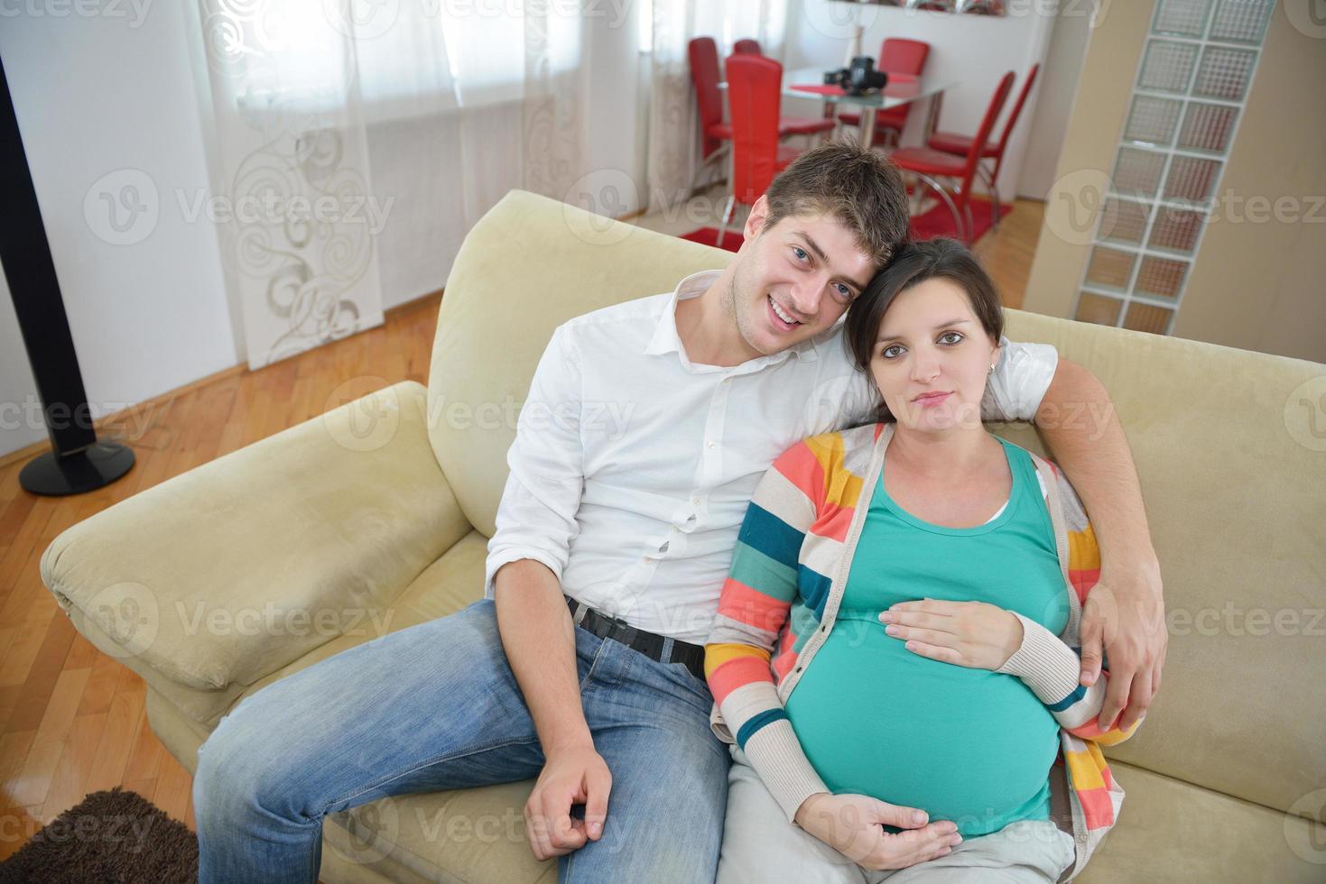 pregnant couple at home using tablet computer photo