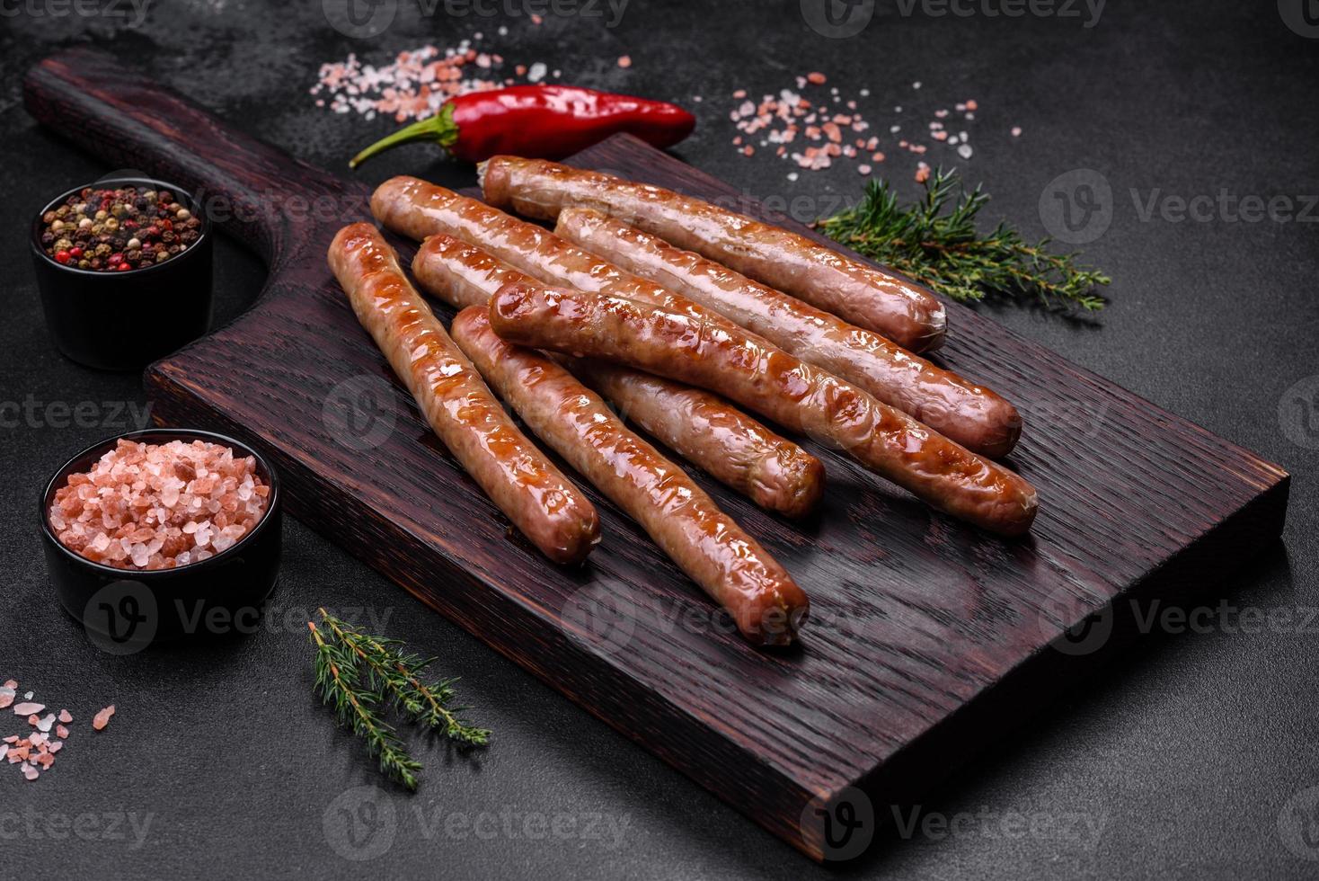 salchicha a la parrilla con la adición de hierbas y verduras en la tabla de cortar de madera foto