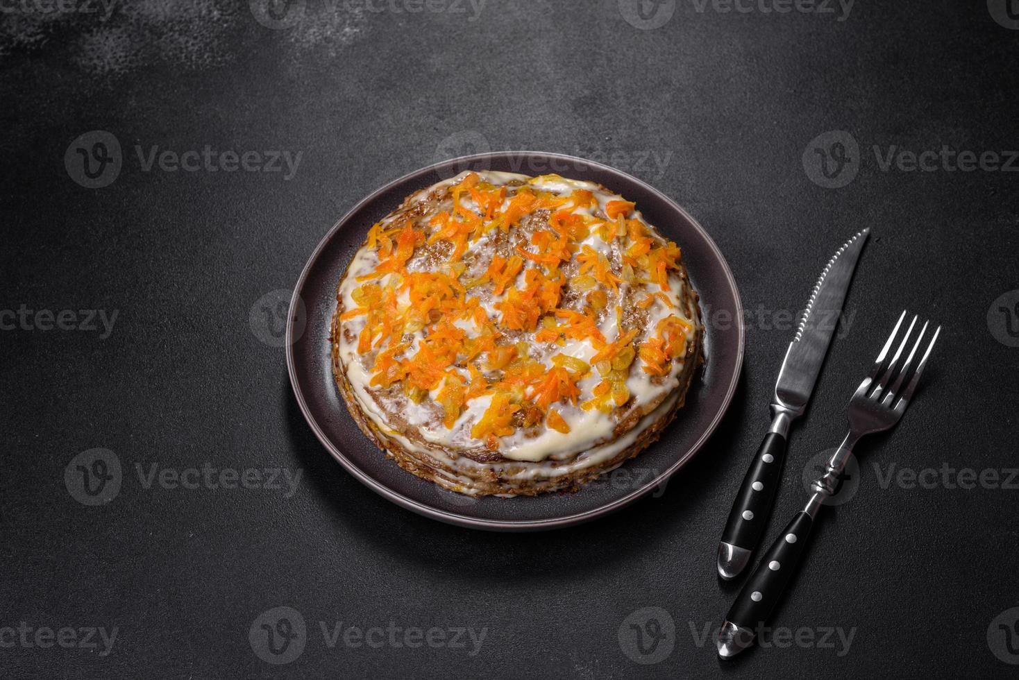 Delicious fresh liver cake with mayonnaise and carrots on a black plate against a dark concrete background photo