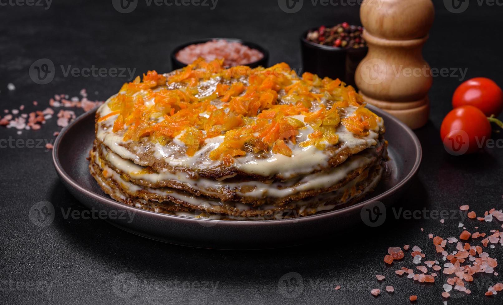 Delicious fresh liver cake with mayonnaise and carrots on a black plate against a dark concrete background photo