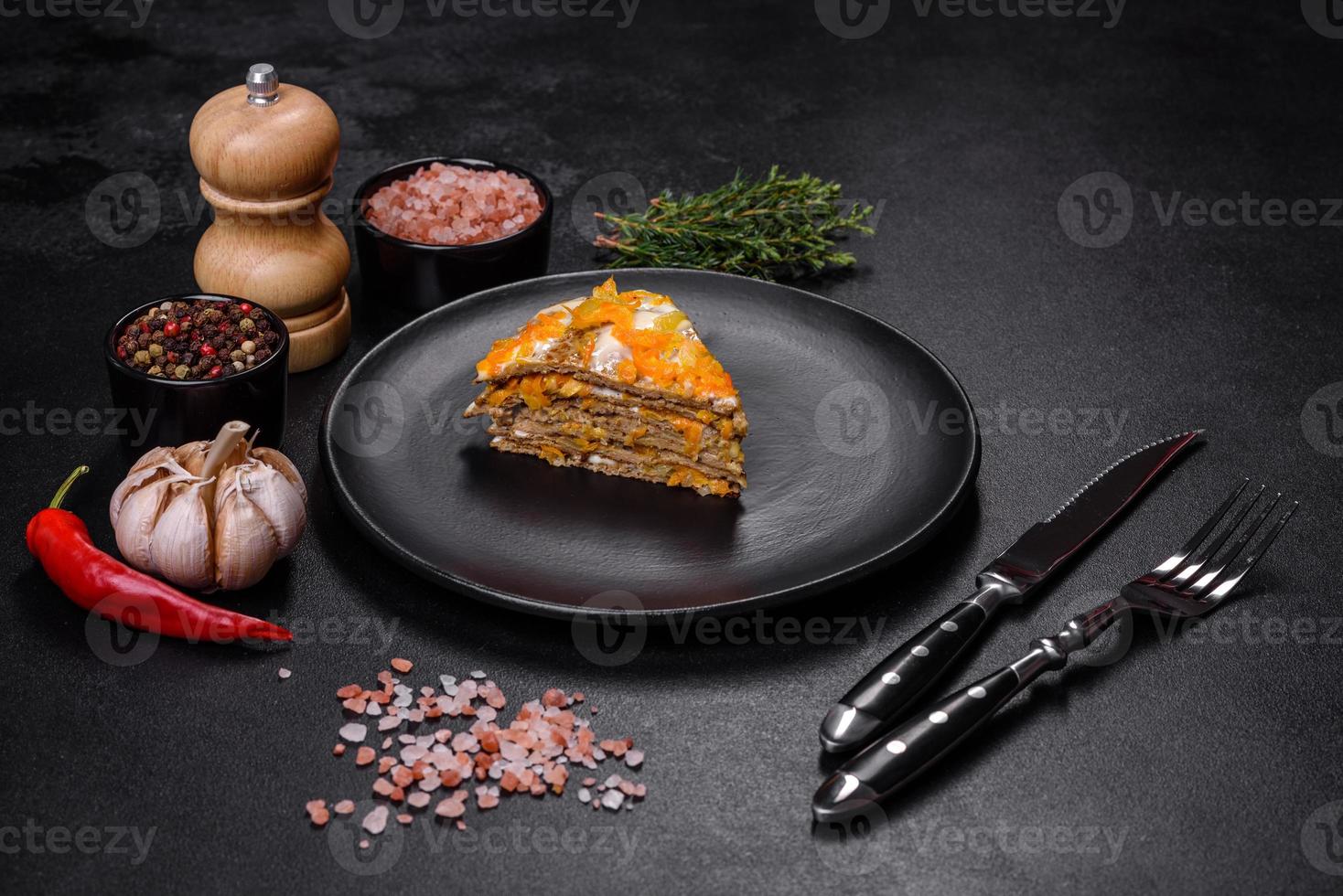 Delicious fresh liver cake with mayonnaise and carrots on a black plate against a dark concrete background photo