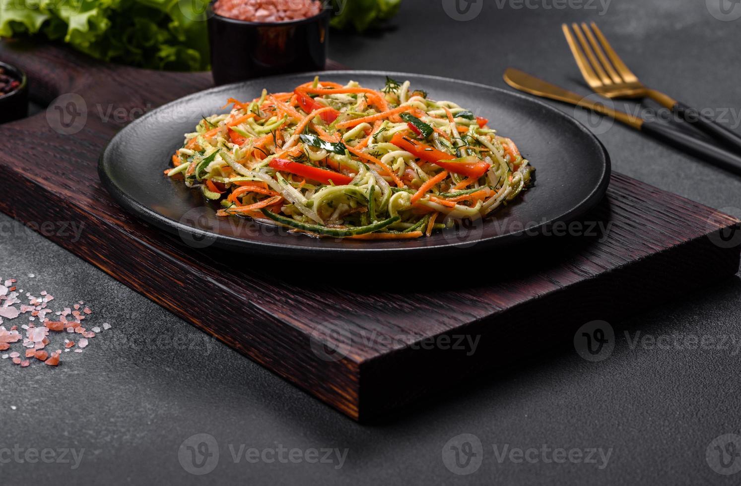 Fresh salad of sliced thin strips of carrot and zucchini on a concrete background photo