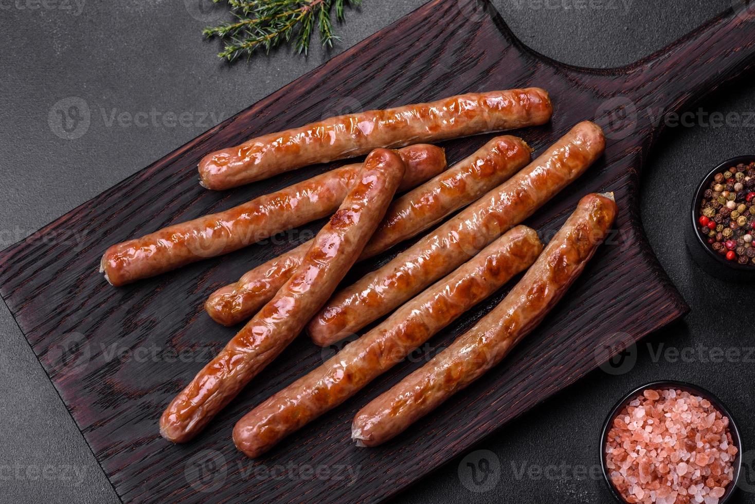 Grilled sausage with the addition of herbs and vegetables on the wooden cutting board photo