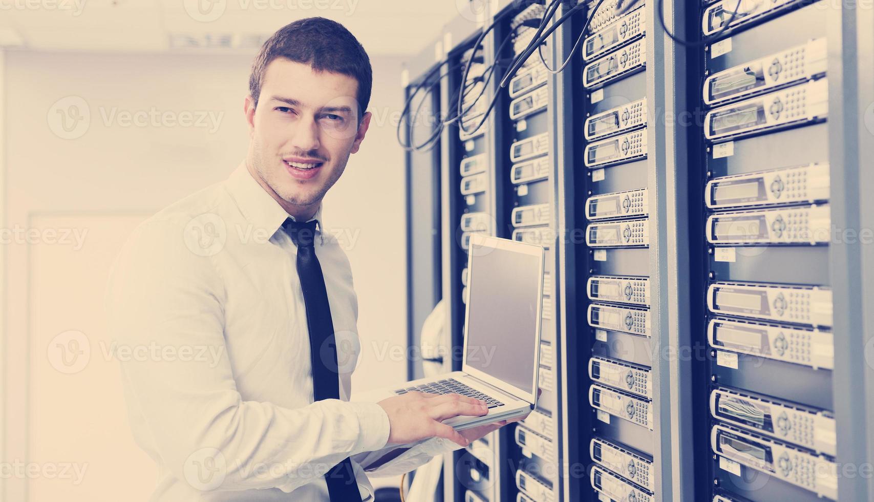 businessman with laptop in network server room photo