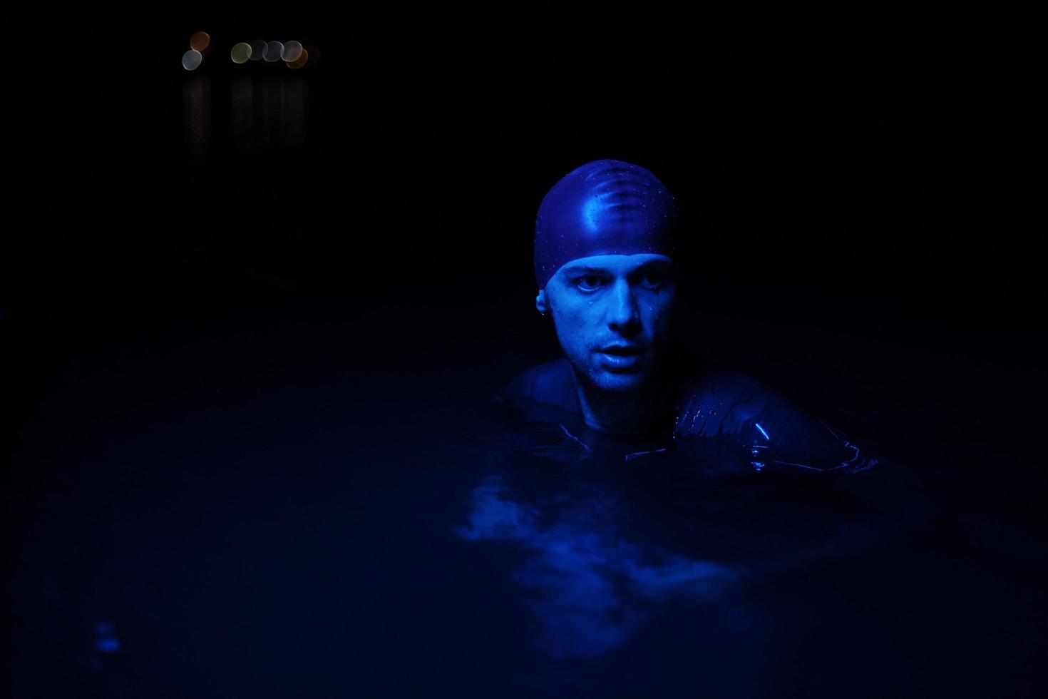 authentic triathlete swimmer having a break during hard training on night neon gel light photo