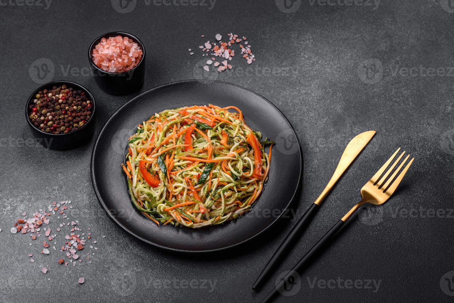 Fresh salad of sliced thin strips of carrot and zucchini on a concrete background photo