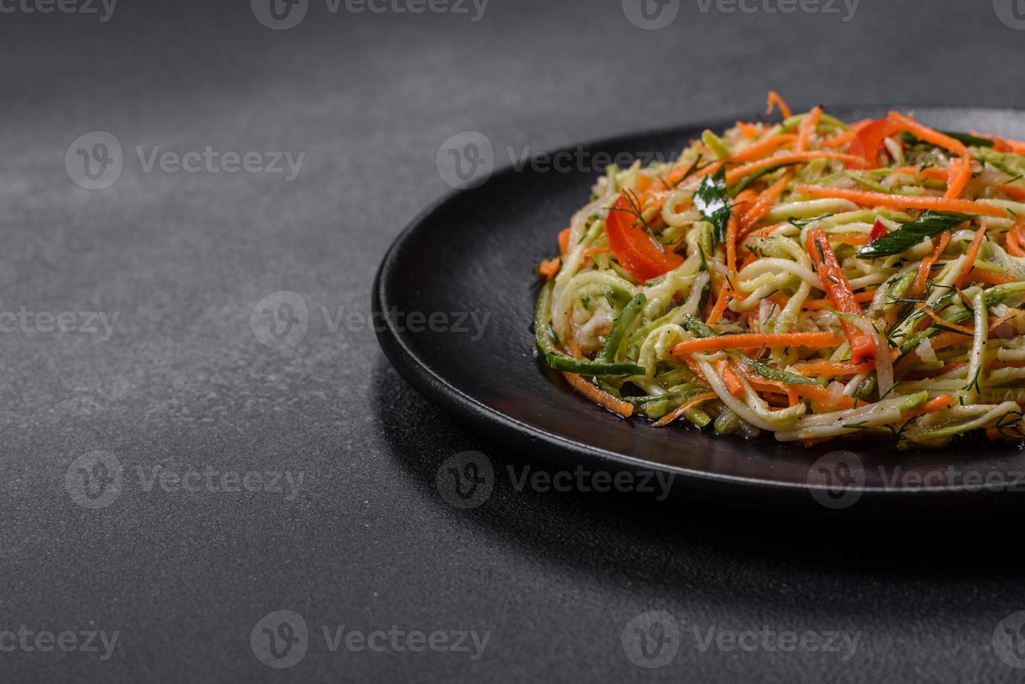 Fresh salad of sliced thin strips of carrot and zucchini on a concrete background photo