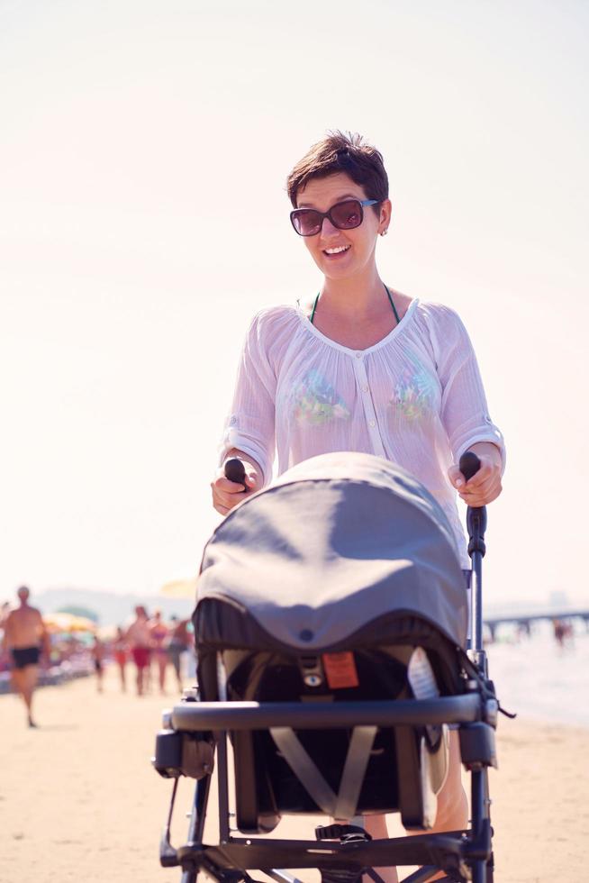 mother walking on beach and push baby carriage photo