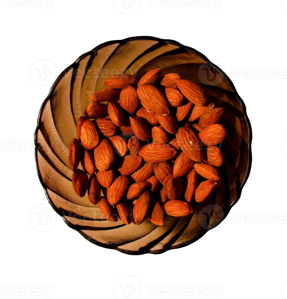 Almonds on a glass brown plate. Isolated on white background. Top view photo