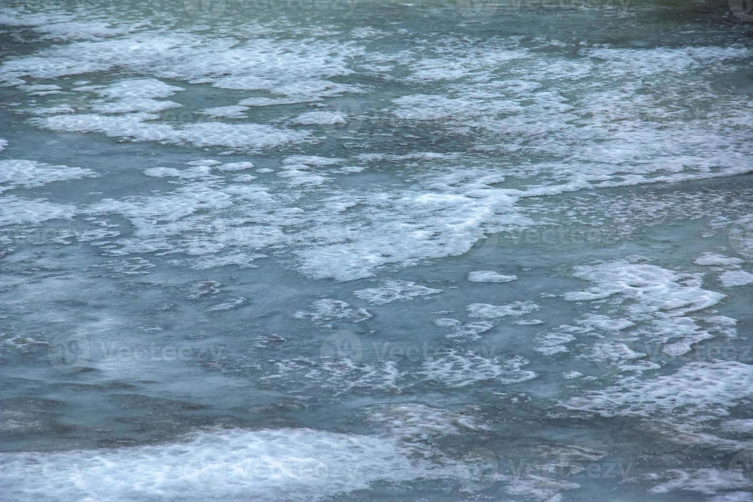 fondo invernal de la superficie helada del río. textura de hielo cubierto de nieve. foto