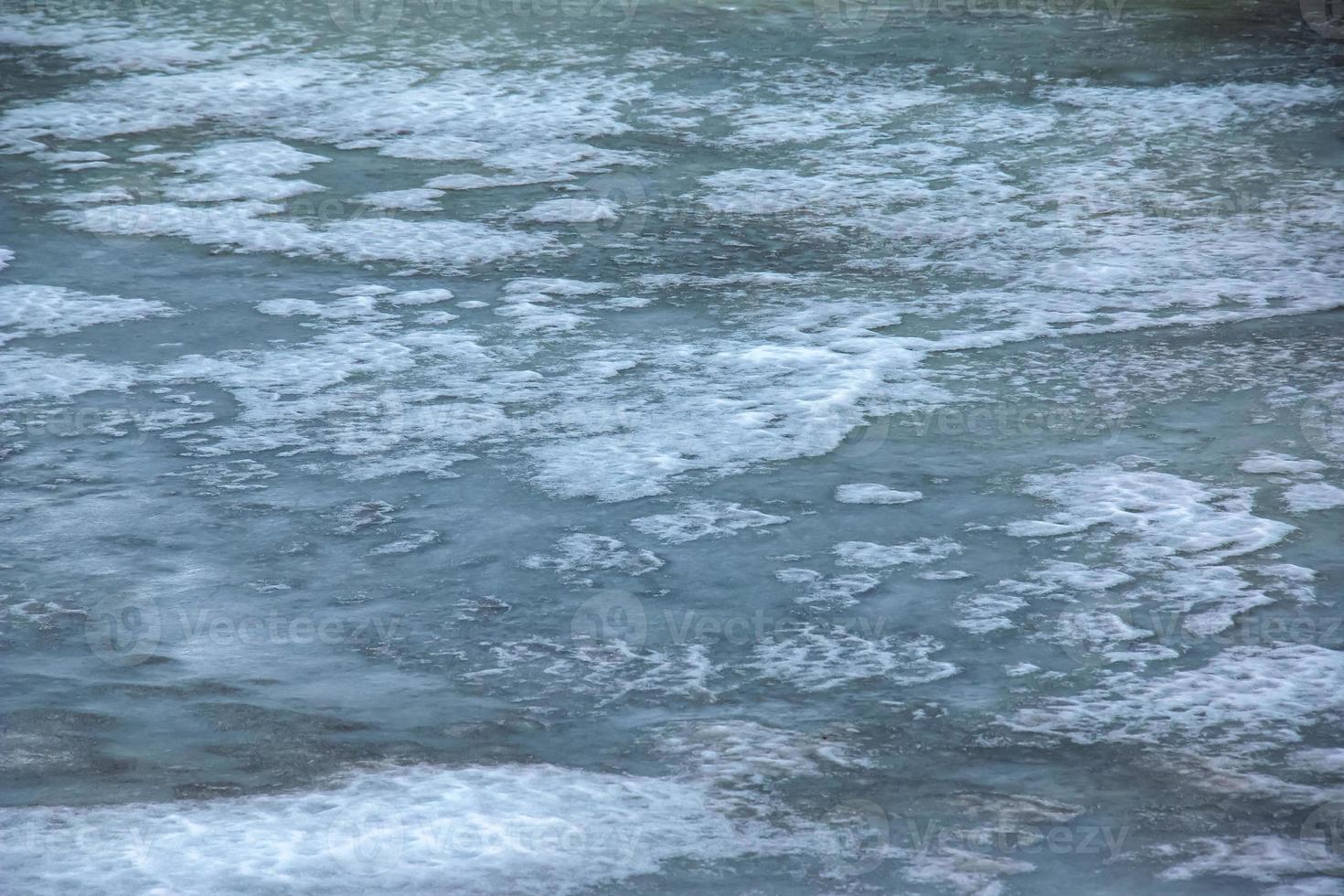 Winter background of the icy surface of the river. Texture of ice covered with snow. photo