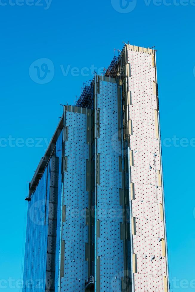 Looking up blue modern office building. A building made of glass and metal in the process of cladding with glass and metal. photo