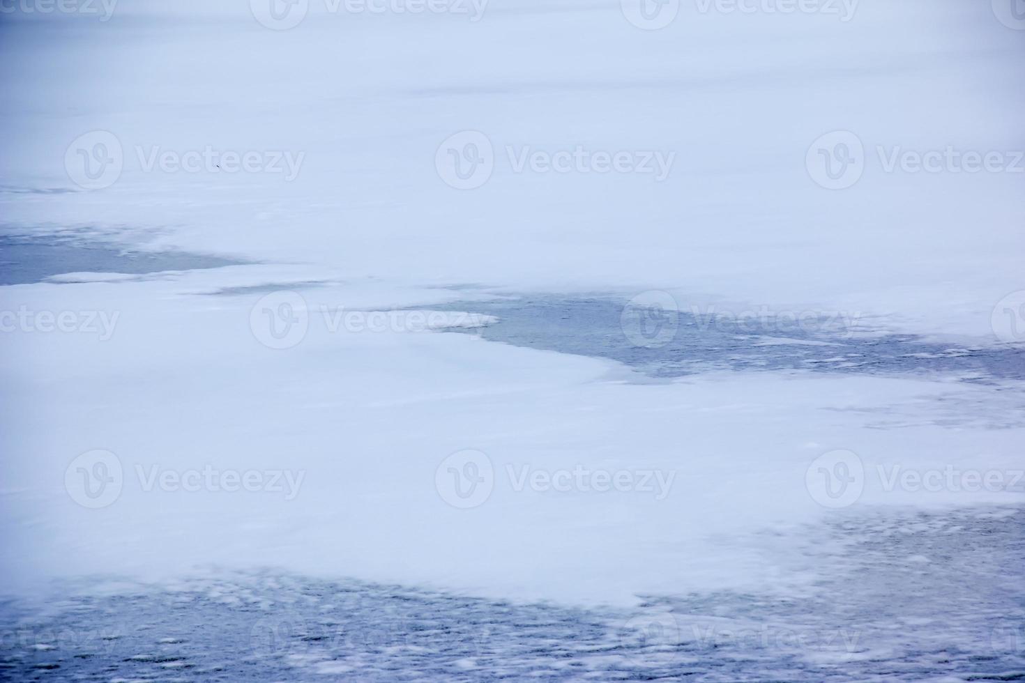 Winter background of the icy surface of the river. Texture of ice covered with snow. photo