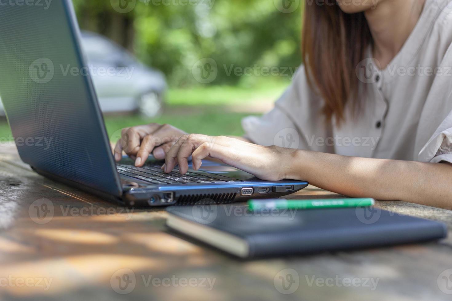 Hands pressed on the laptop keyboard on the desk outdoors in the shady atmosphere suitable for working. photo