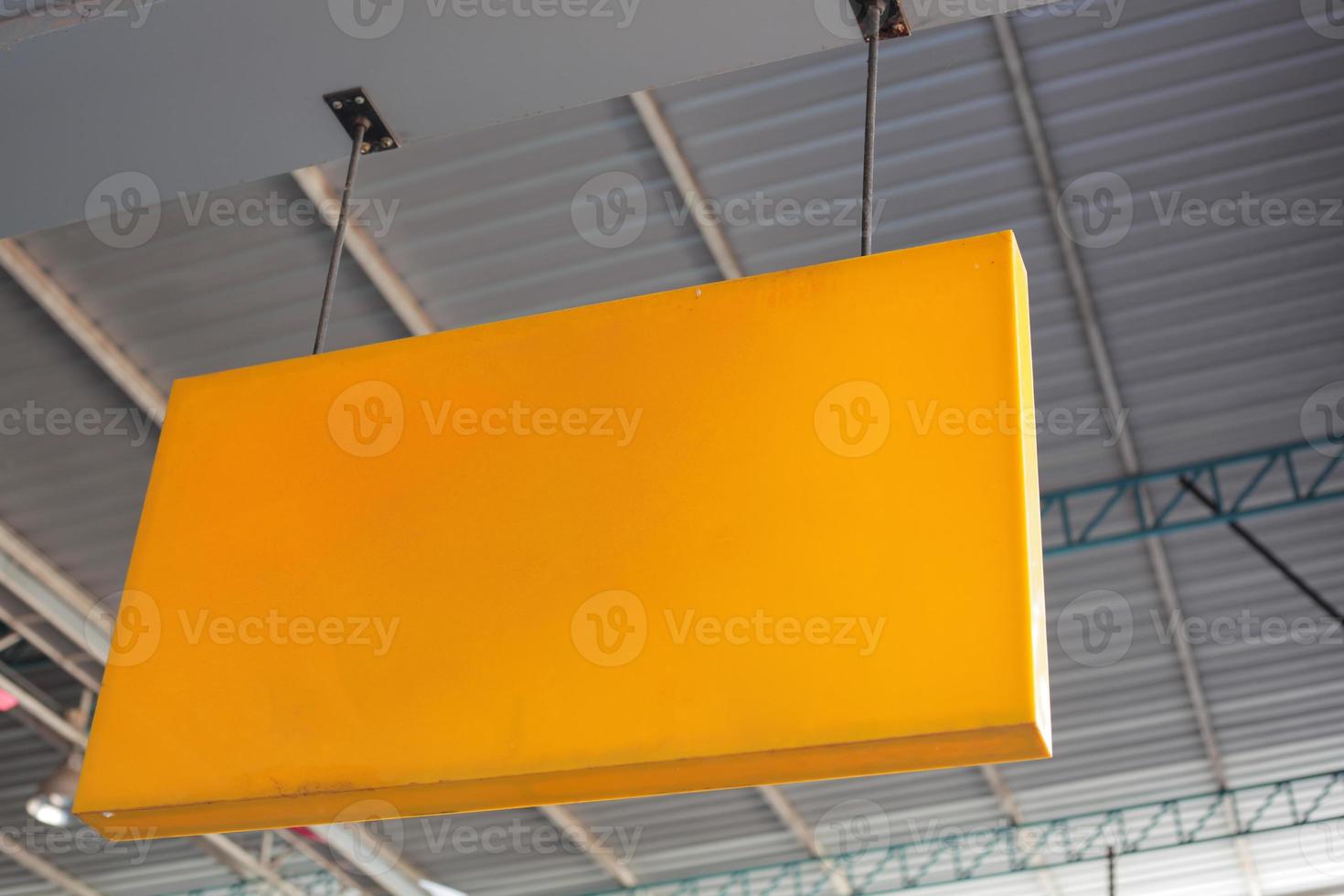 An orange and yellow shop name hanging sign mounted on the ceiling. photo
