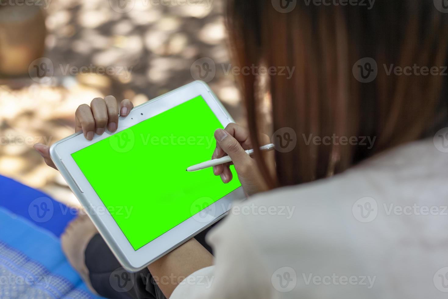 Woman's hand holding tablet and pen taking note of something with green space for text or online media. photo