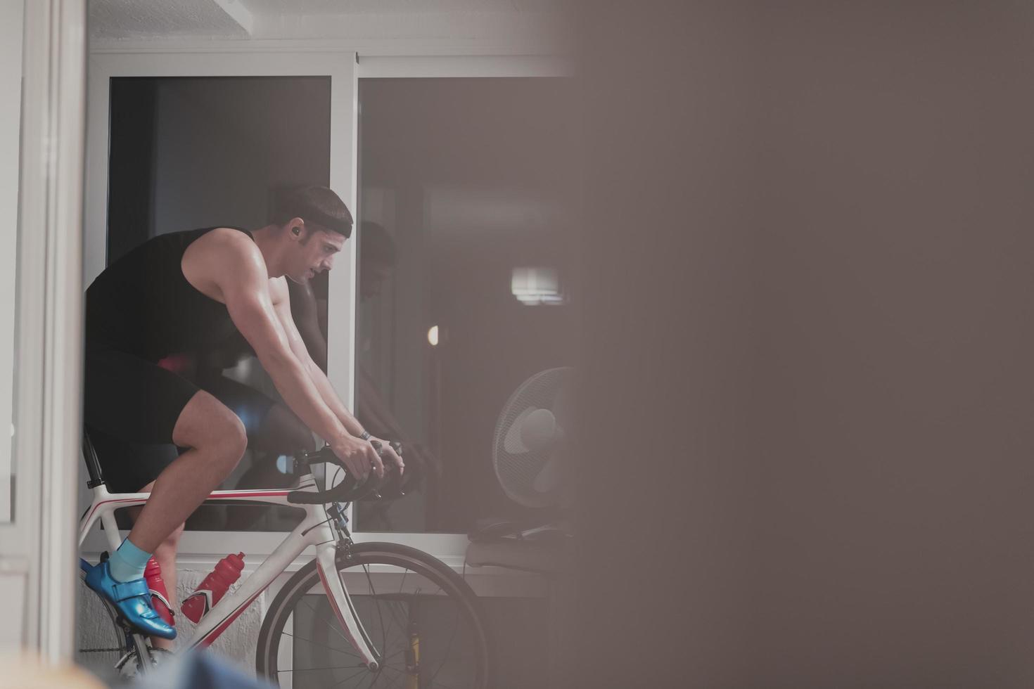 Man cycling on the machine trainer he is exercising in the home at night playing online bike racing game photo