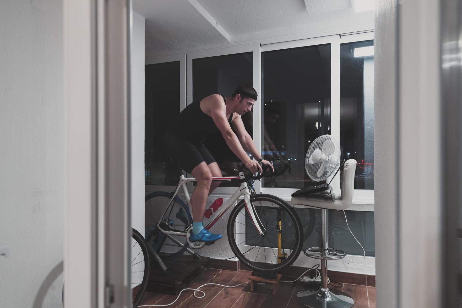 Man cycling on the machine trainer he is exercising in the home at night playing online bike racing game photo