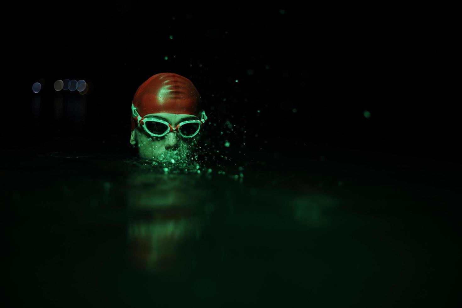 authentic triathlete swimmer having a break during hard training on night neon gel light photo