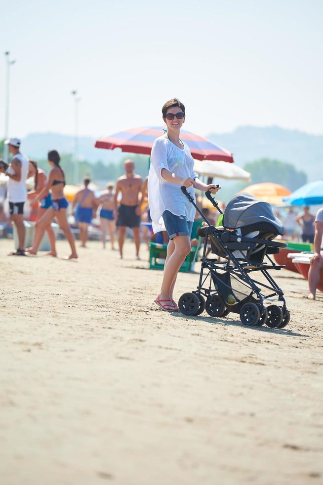 mother walking on beach and push baby carriage photo