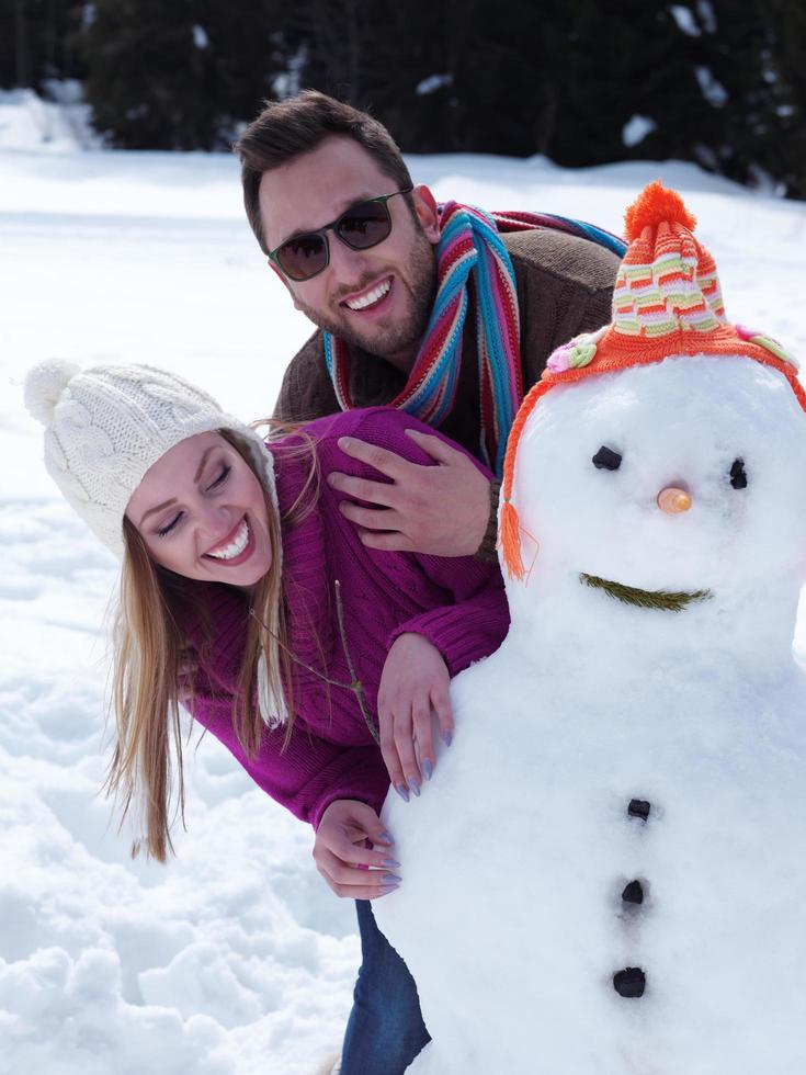 retrato, de, feliz, pareja joven, con, muñeco de nieve foto