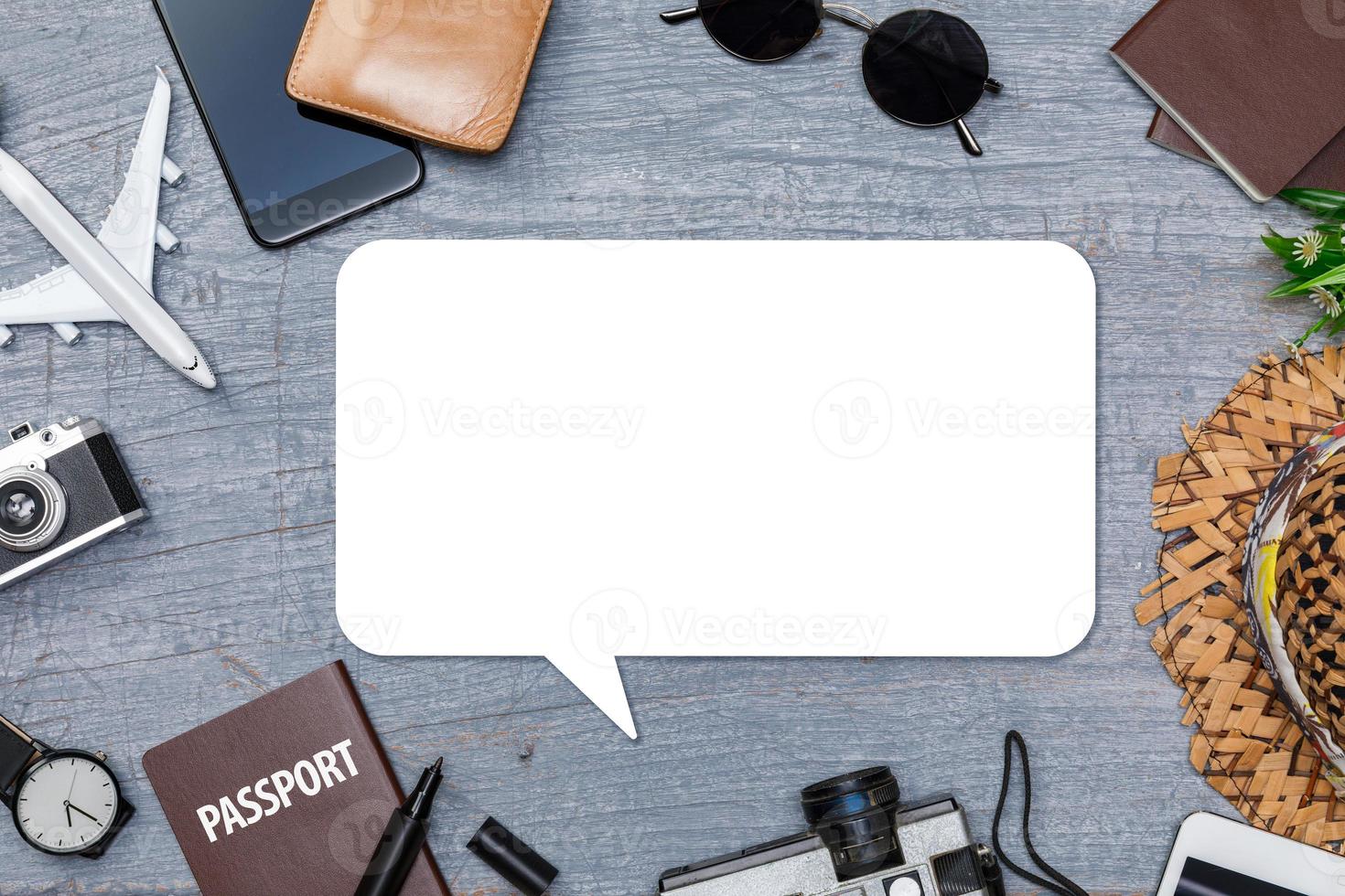 Blank speech bubbles with Traveler's accessories with passport, books of travel plan, wallet, camera, hat, backpack and airplane toy on blue wooden desk, Flat lay with copy space photo