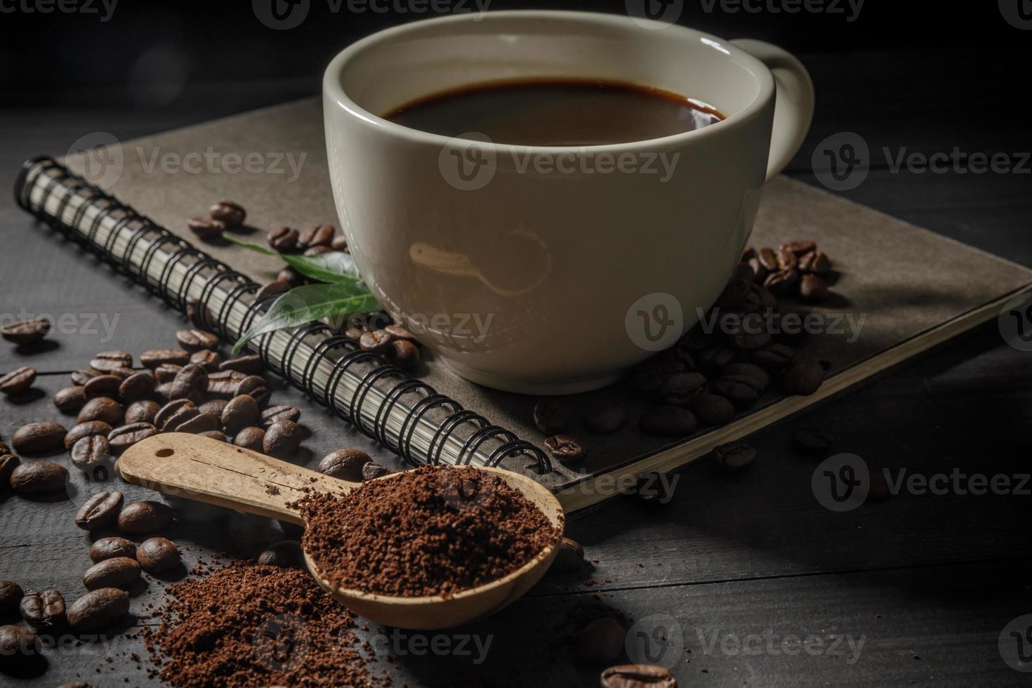 Hot coffee cup with coffee beans and the ground powder of coffee on the wooden table photo