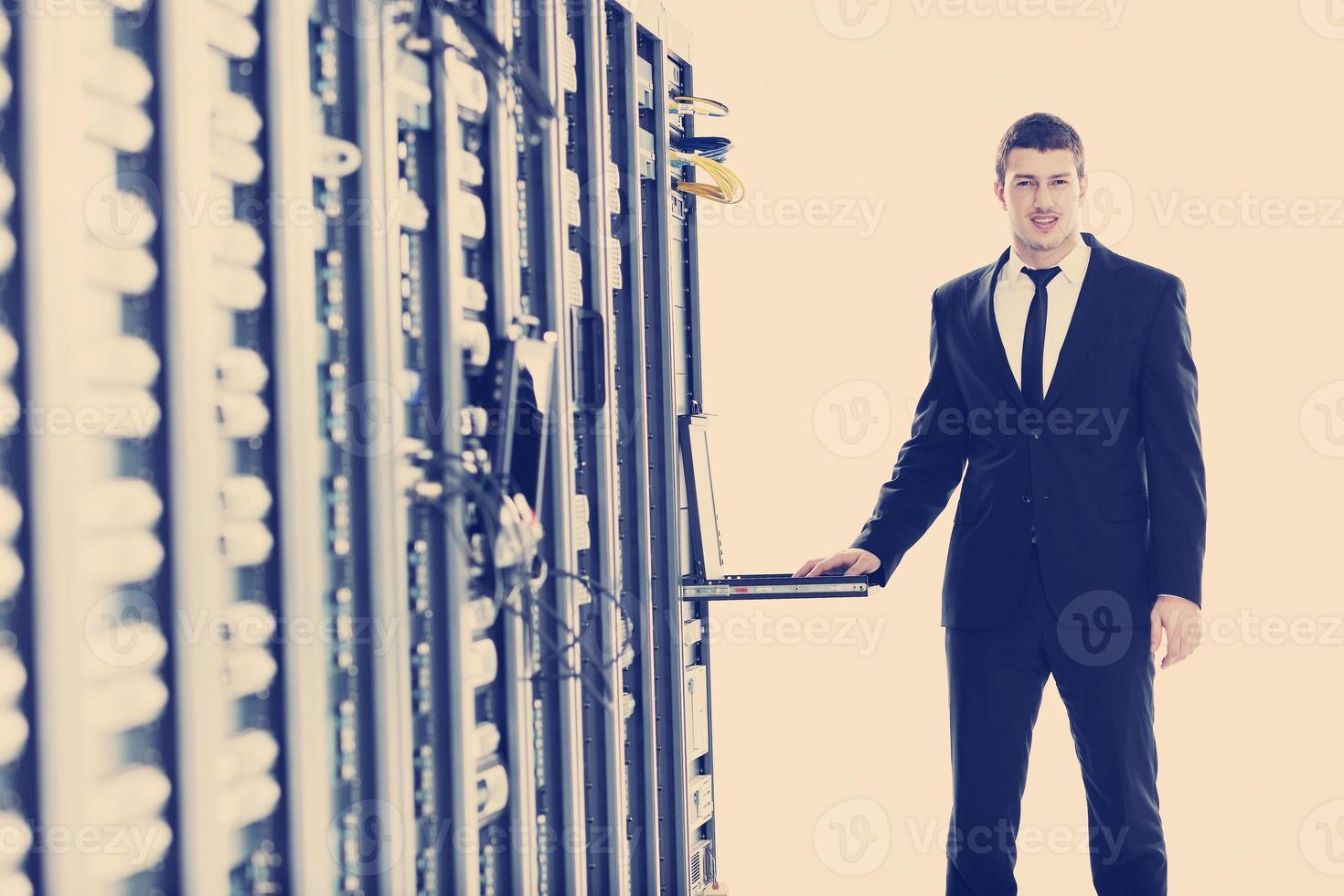 businessman with laptop in network server room photo