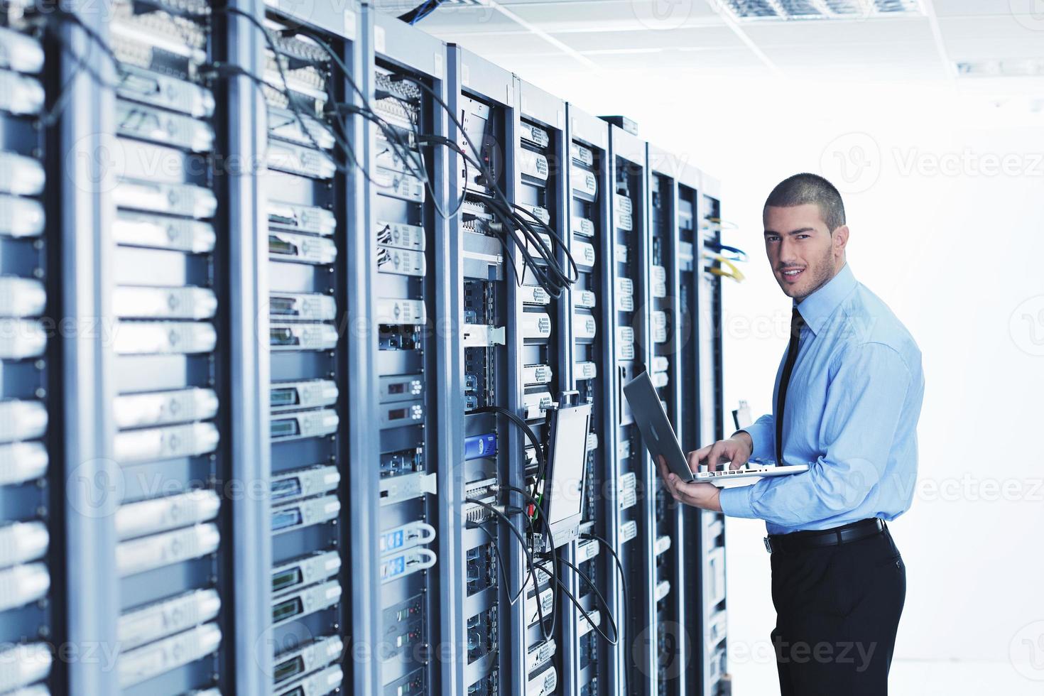 businessman with laptop in network server room photo