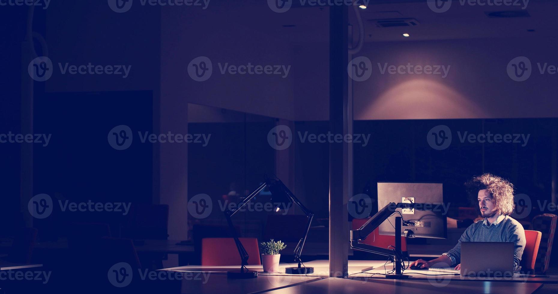 man working on computer in dark office photo