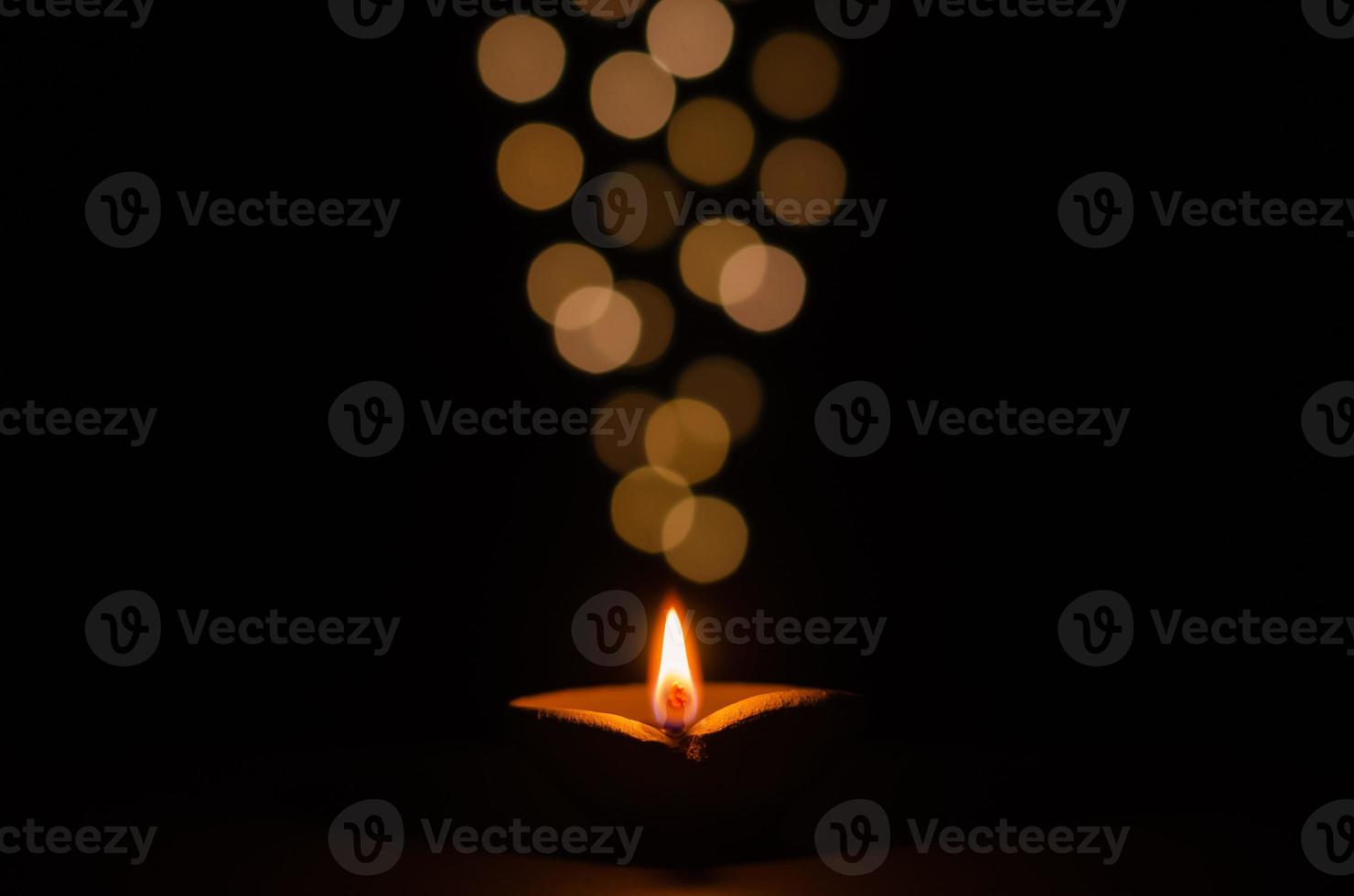 Clay diya lamp lit on dark background with bokeh lights. Diwali festival concept. photo