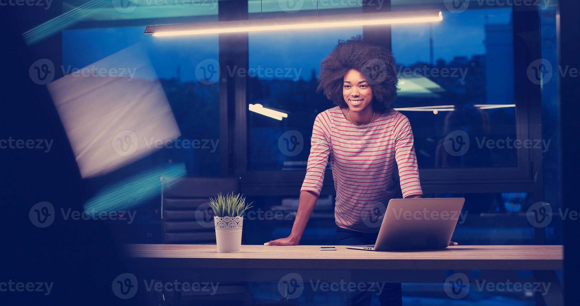 mujer de negocios negra que usa una computadora portátil en la oficina de inicio nocturno foto