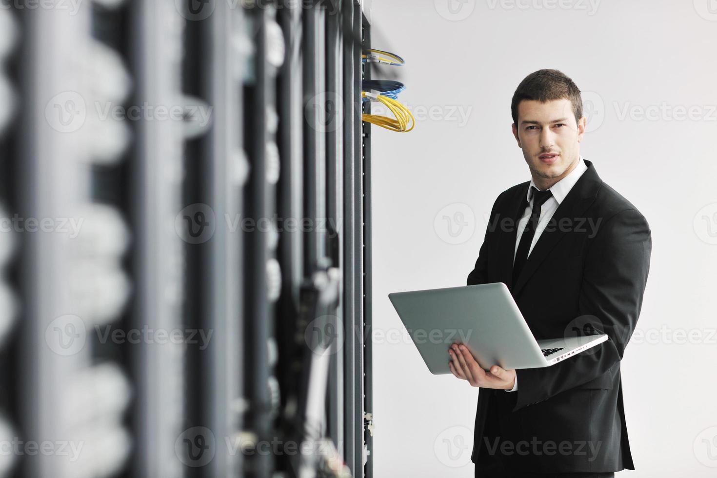 businessman with laptop in network server room photo