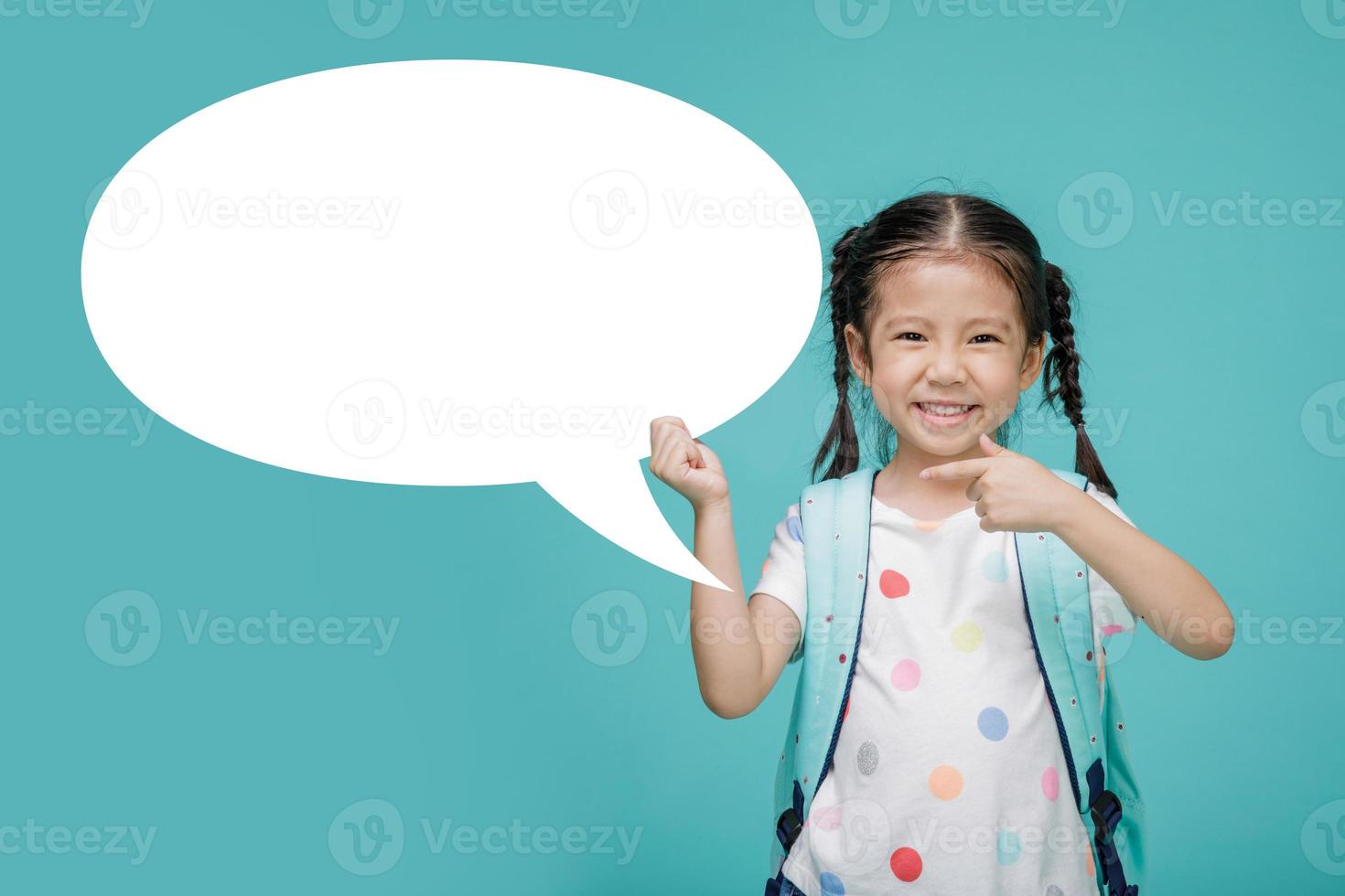 Excited young Asian little girl with empty speech bubble, empty space in studio shot isolated on colorful blue background, Educational concept for school photo