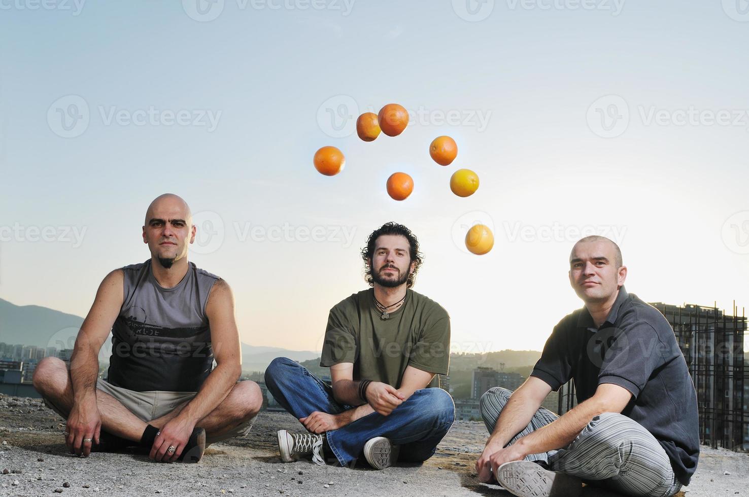 three man outdoor play with orange fruit photo