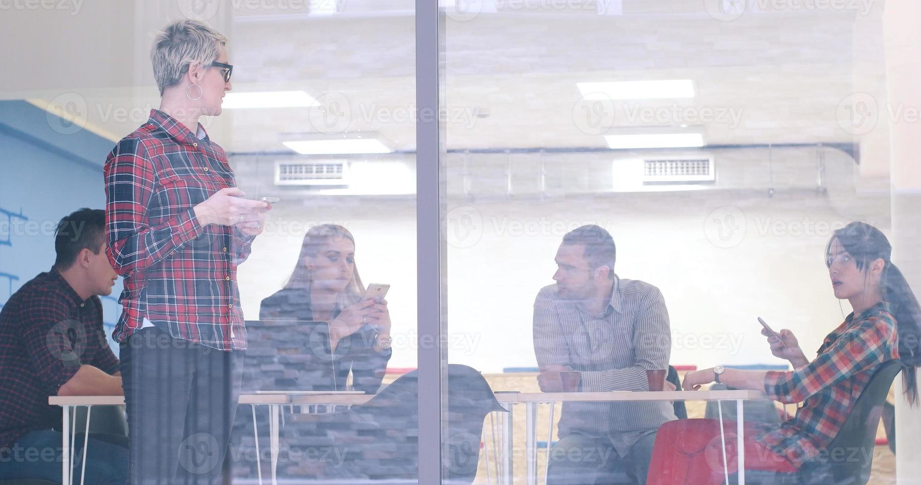 Business Woman Looking Through A Window And using On A Cell Phone during bussines meeting photo