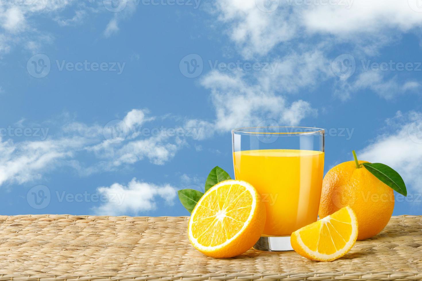 Glass of fresh orange juice on a rattan basket, Fresh fruits Orange juice in glass with group on blue sky background with copy Space for your text. photo