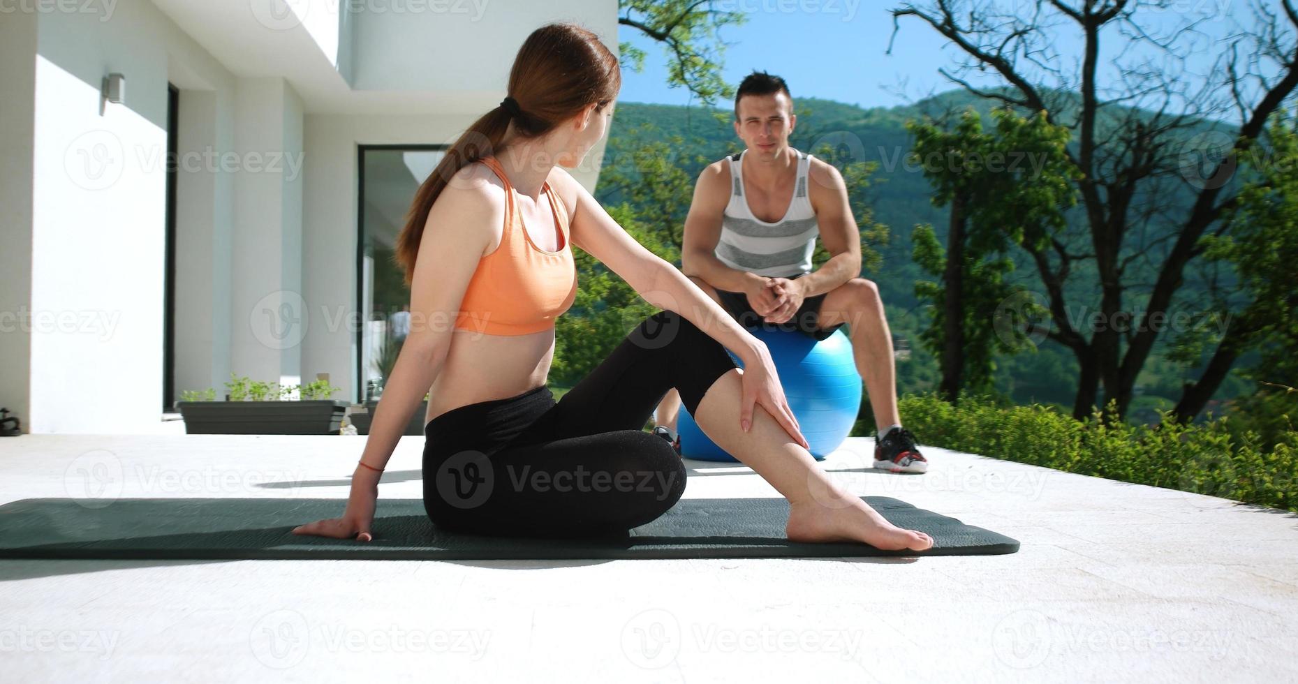 Couple Doing Stretching Exercises Together in front of luxury villa photo