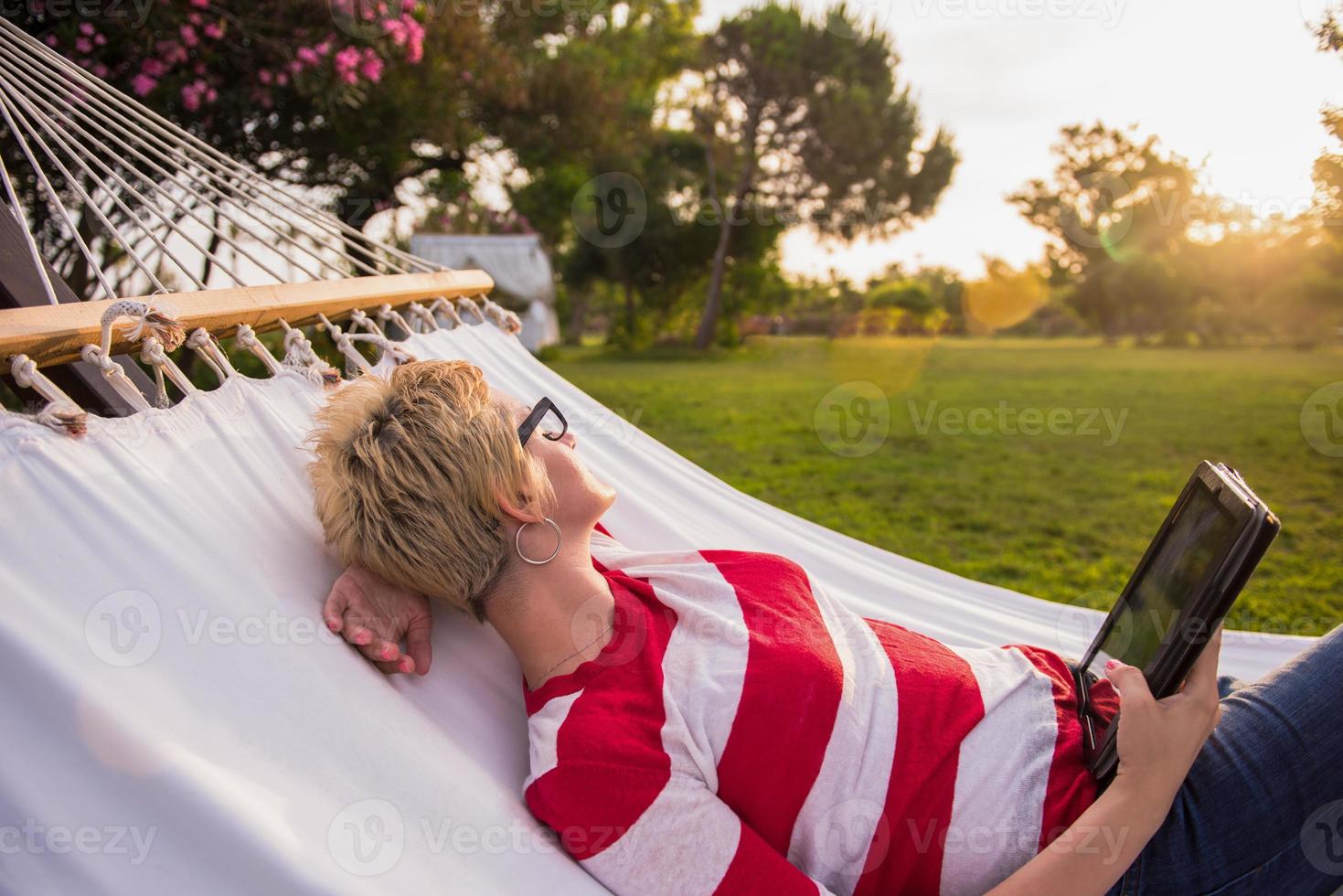 woman using a tablet computer while relaxing on hammock photo