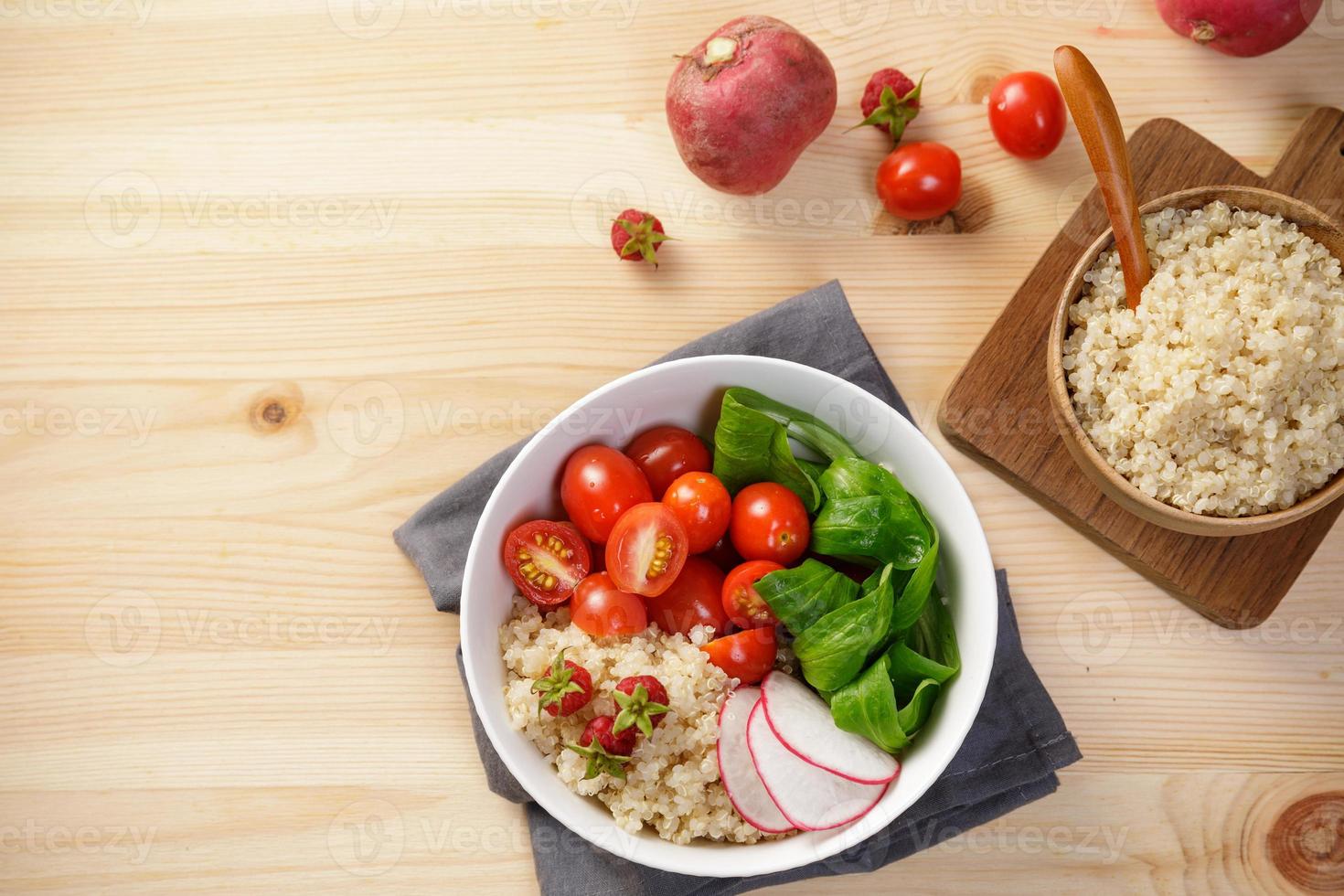 Quinoa salad with vegetables, raspberry and tomatoes on the wooden table. Super food for healthy and concept of balanced diet photo