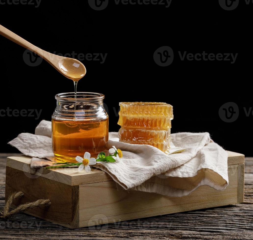 abeja de miel en tarro y panal con cucharón de miel y flor en mesa de madera, productos de abeja por concepto de ingredientes naturales orgánicos, espacio de copia para su texto foto