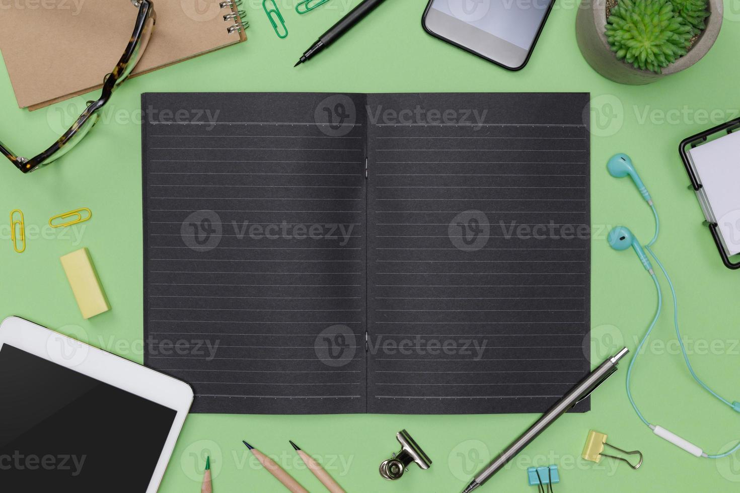 Top view workspace office supplies mockup with tablet, glasses, books and accessories isolated on green background, overhead view with copy space, Workspace for designer concept photo