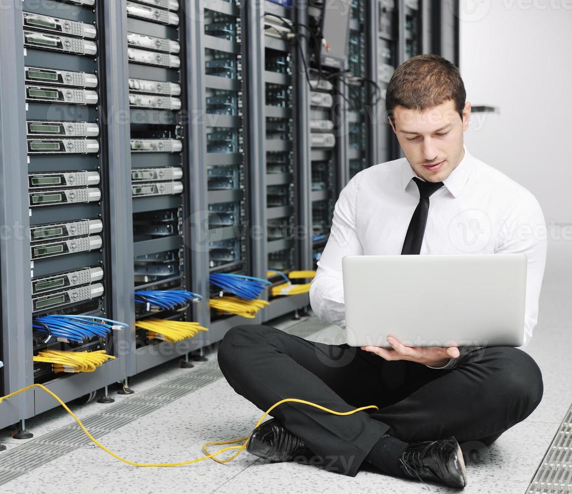 businessman with laptop in network server room photo