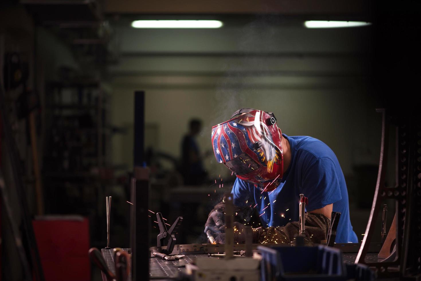 soldador profesional de la industria pesada que trabaja dentro de la fábrica, usa casco y comienza a soldar. enfoque selectivo foto