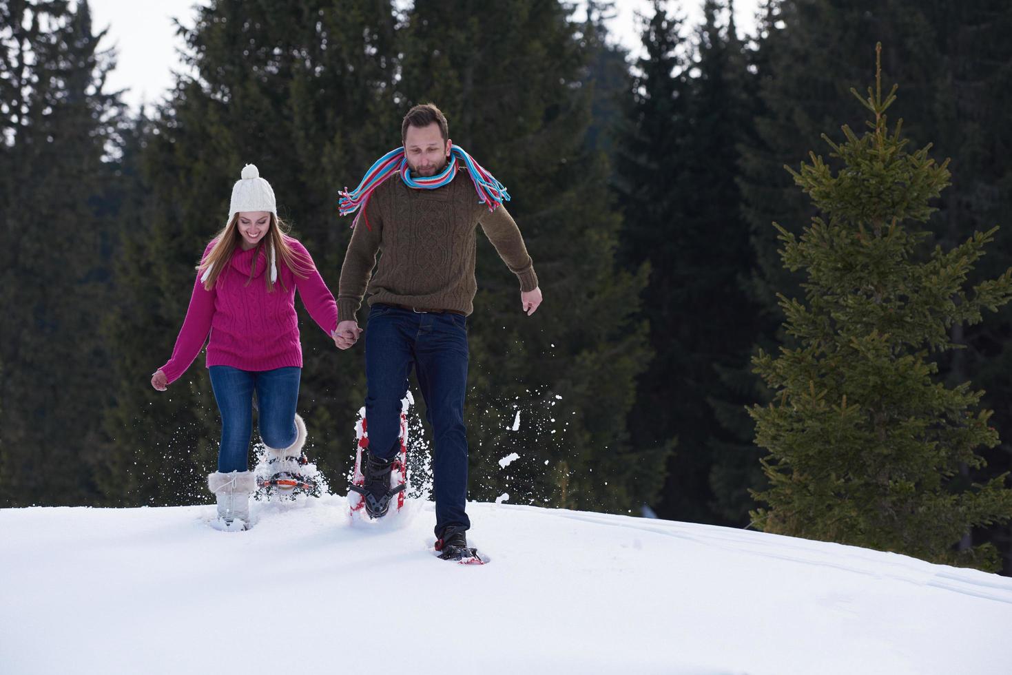 couple having fun and walking in snow shoes photo