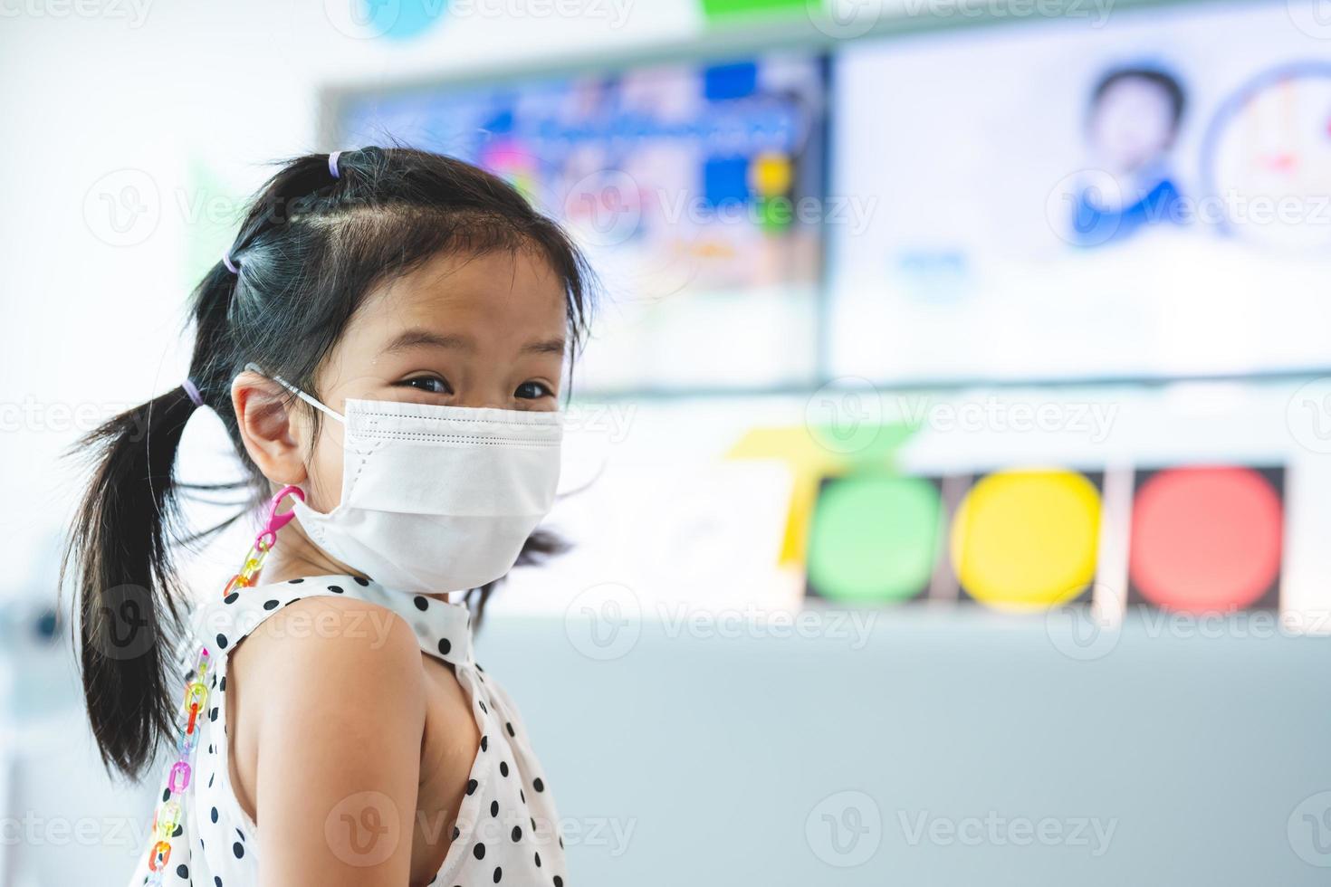 Portrait image child 5-6 years old. Cute girl wearing white face mask while learning about traffic lights before taking test ride on bicycle on mock road. Kid are excited and happy to learn new things photo