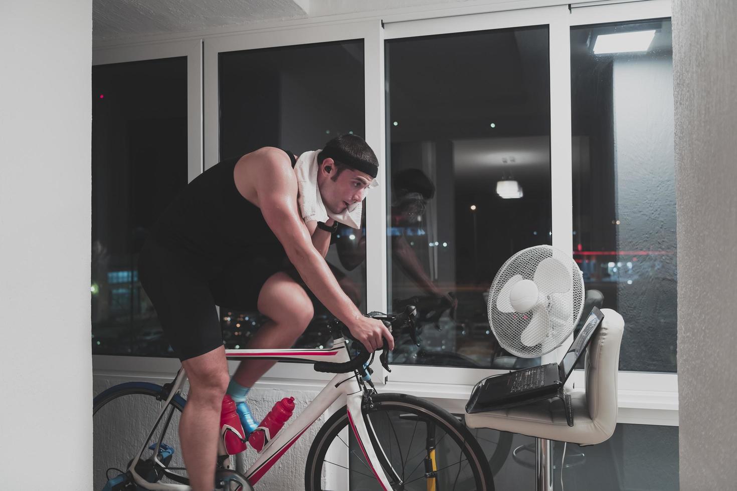 Man cycling on the machine trainer he is exercising in the home at night playing online bike racing game photo