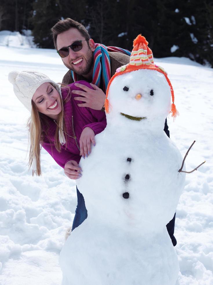 portrait of happy young couple with snowman photo