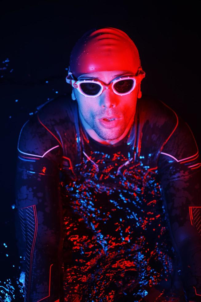 authentic triathlete swimmer having a break during hard training on night neon gel light photo