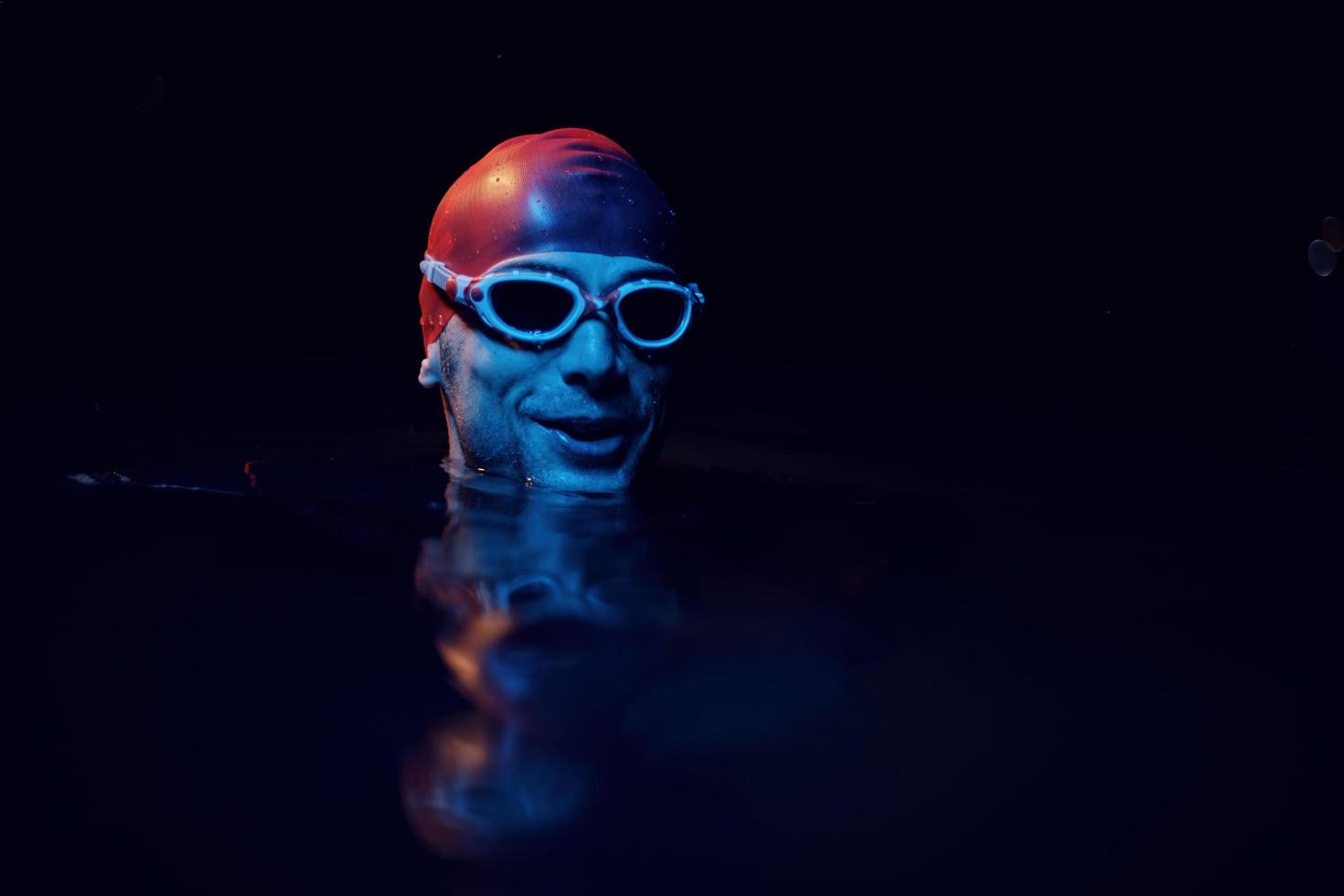 authentic triathlete swimmer having a break during hard training on night neon gel light photo